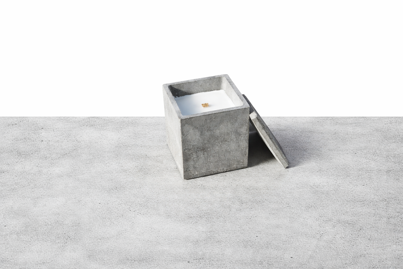 Cubo Grande Graue, quadratische Betonkerze mit offenem Deckel auf einer glatten Oberfläche.