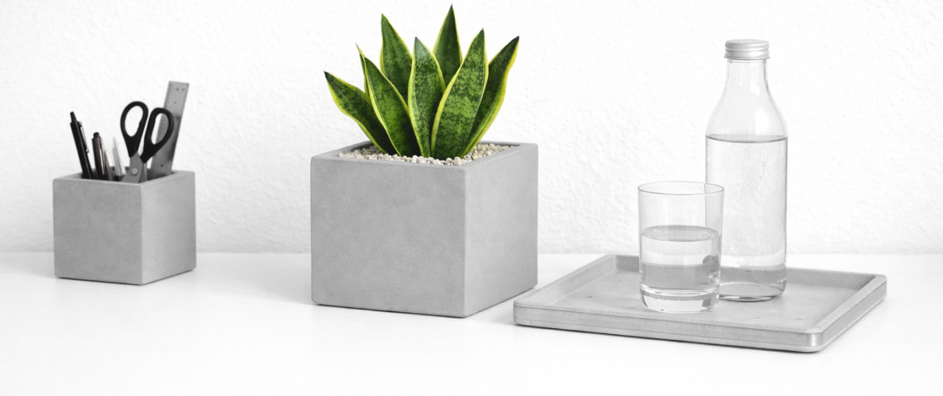 Stilvolle Tischagentur mit einem Pflanzenbehälter, Glas, Wasserflasche und Stifthalter.