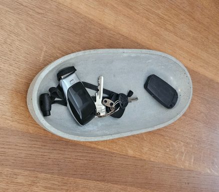 Ein graues Tablett mit einem Autoschlüssel und mehreren Schlüsselbund.